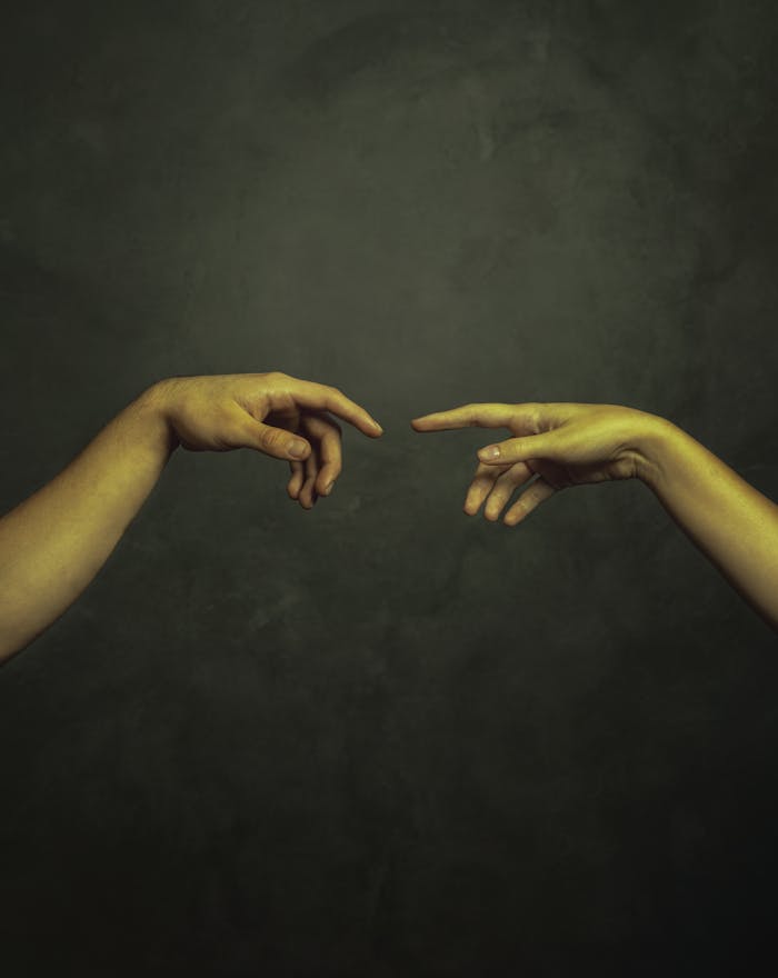 Contact Two hands reaching towards each other against a dark background in an artistic style.